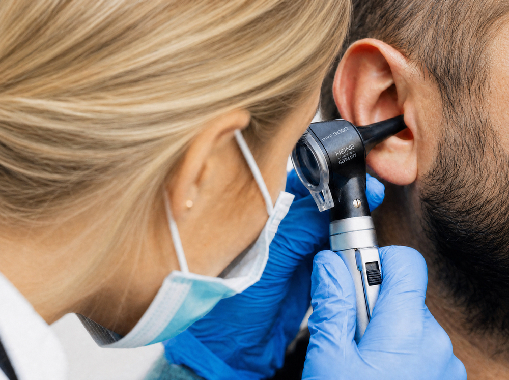 Doctor of Audiology examining a patient's ear canal with an otoscope before professional earwax removal at Hughes Holistic Audiology in Zionsville, IN